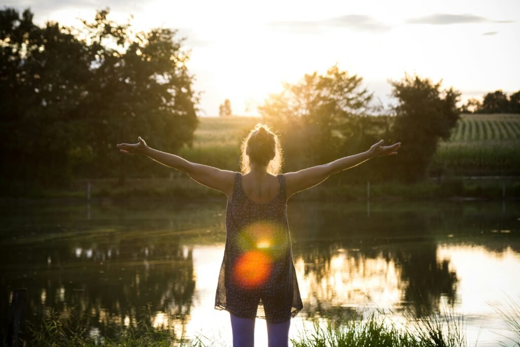 Relaxamento e autocuidado ao ar livre, com uma mulher apreciando a paisagem ao entardecer.