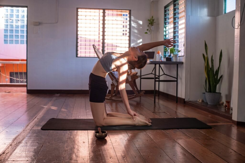 "Mulher fazendo yoga em casa, em uma posição de alongamento, promovendo equilíbrio emocional e redução do estresse através de práticas físicas."